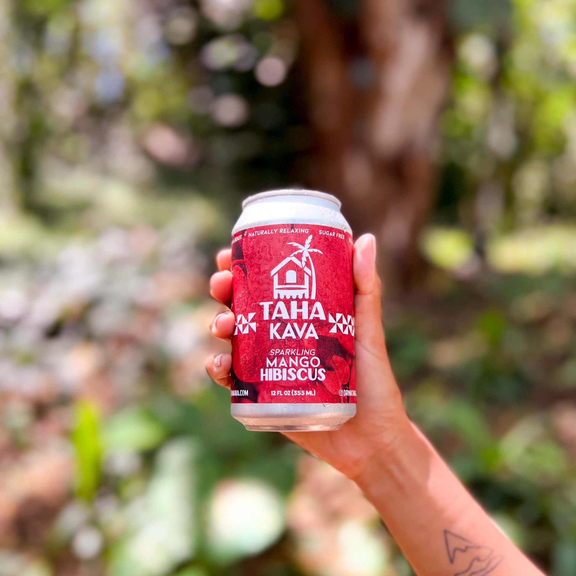 Hand holding Mango Hibiscus Taha Kava can in a tropical setting