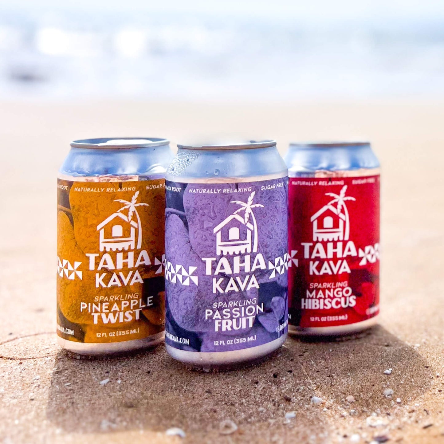 All three Taha sparkling kava flavors displayed on a beach